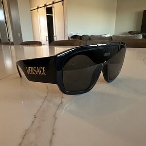 Versace VE4439 shield sunglasses in black with dark grey lenses.